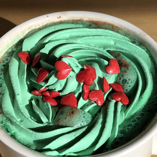 Hot Chocolate with green whipped cream and heart sprinkles.